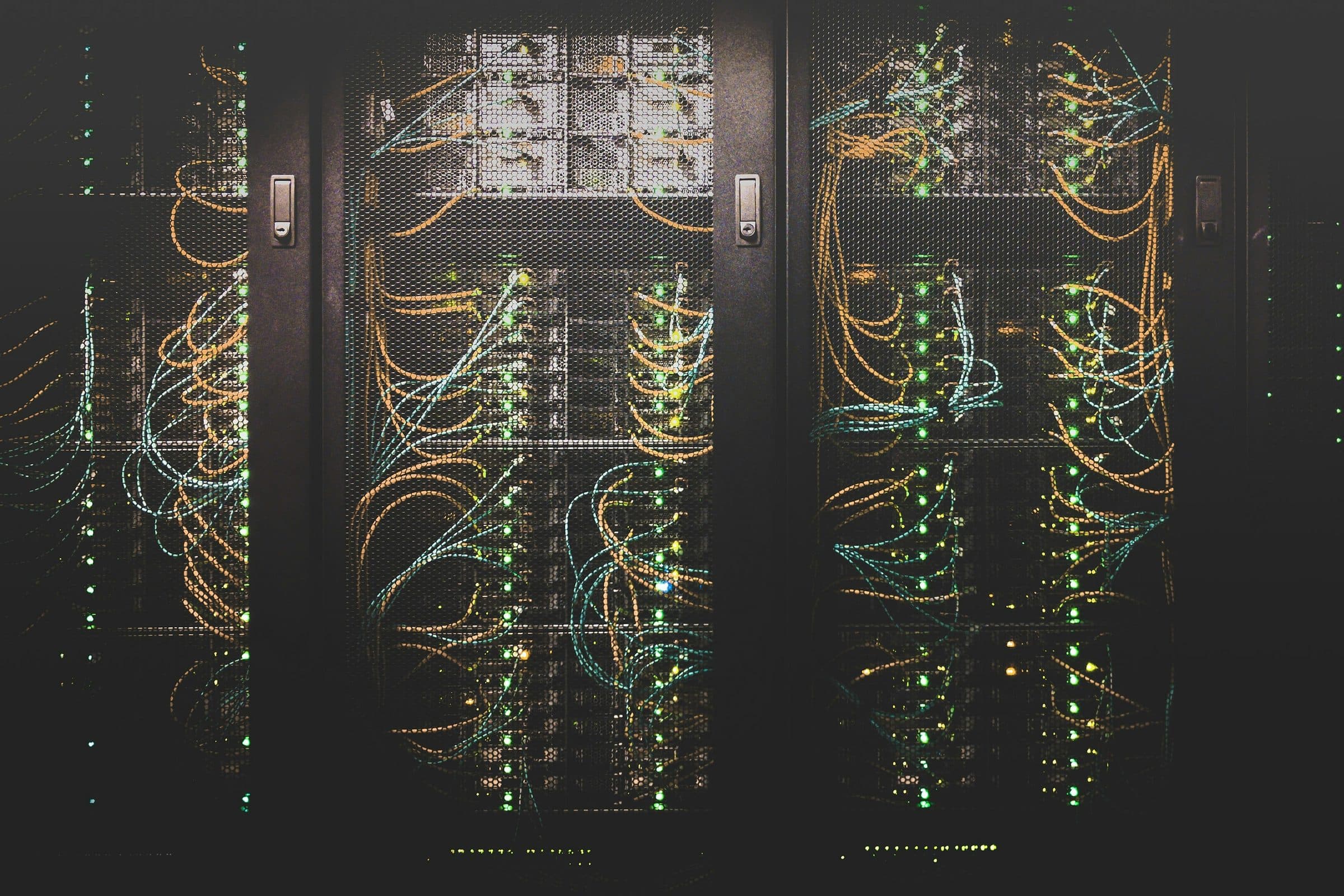 Armadi rack di rete con cavi ordinati e spie verdi accese, dietro porte a rete
